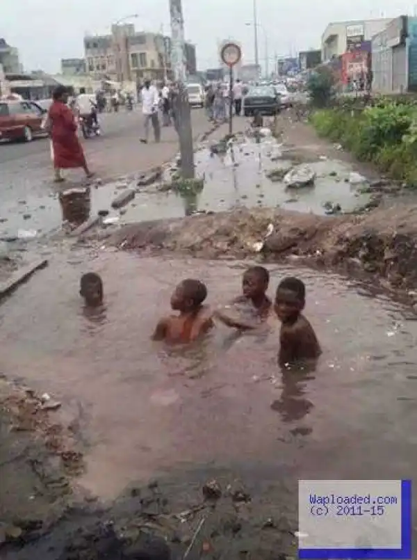 Photo of children bathing inside a large water-filled pothole